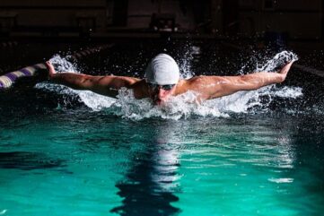 Swimmer performing butterfly stroke in a splashing indoor pool