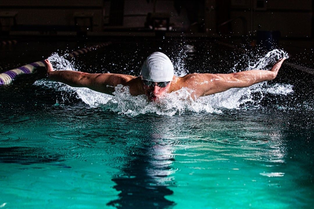 Swimmer performing butterfly stroke in a splashing indoor pool