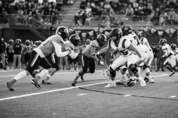 Football players execute a running play as defenders close in