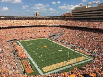 Packed Tennessee football stadium with orange-clad fans surrounding the field