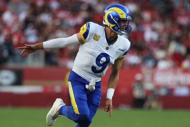 Rams quarterback in uniform running across a football field